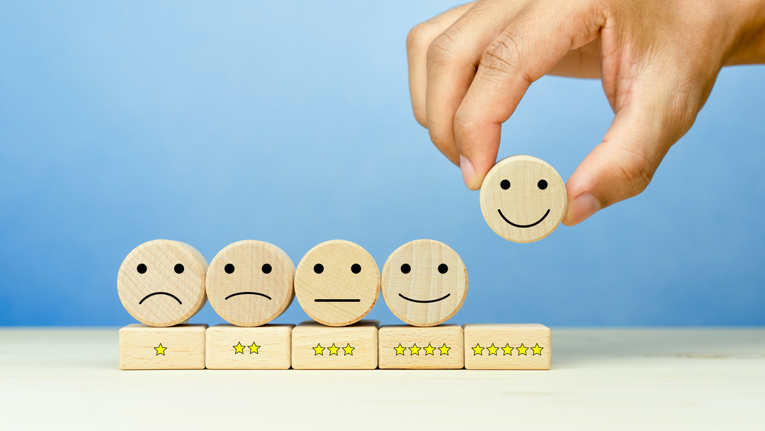 customer service evaluation and satisfaction survey concepts. the client's hand picked the happy face smile face icon and five star symbol on wooden cube on table